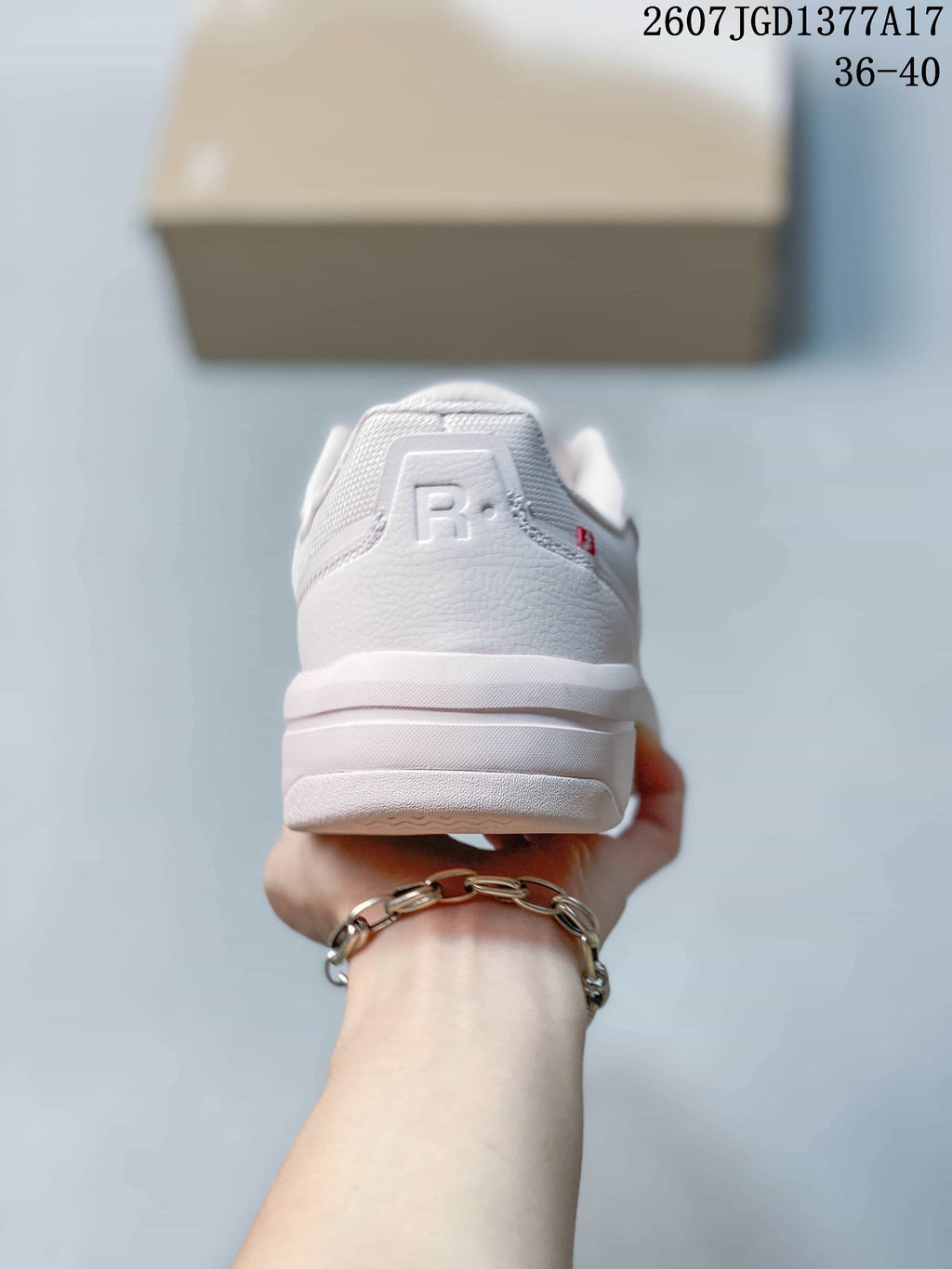 Rear view of the white and pale pink sneaker showing the padded heel, layered sole, and heel branding detail.