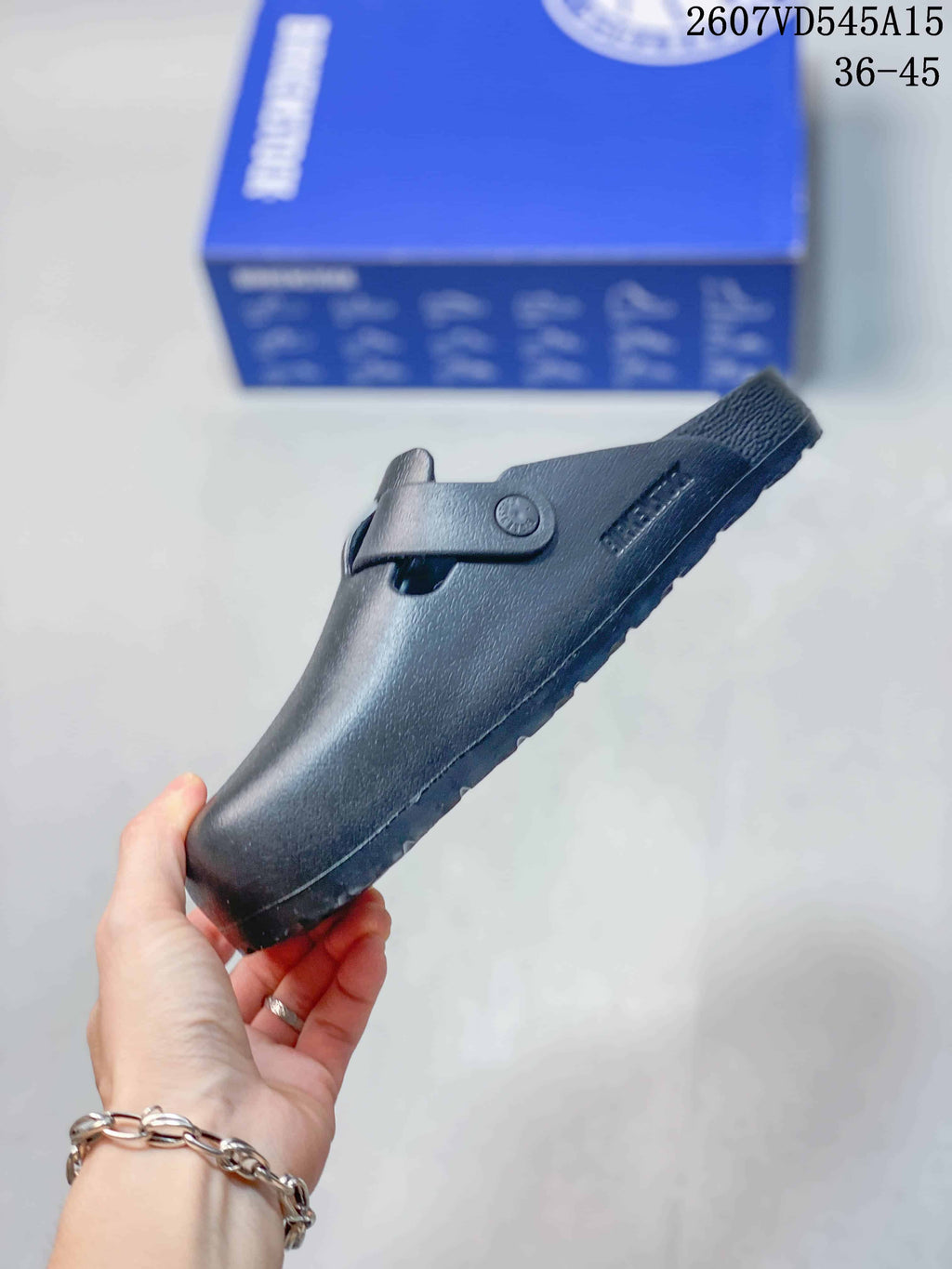 Side profile of the black sandal showing the closed toe, buckle strap and textured sole.