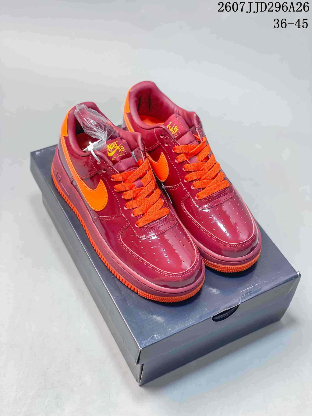 Pair of burgundy and orange low-top Nike Air Force 1 sneakers displayed on a shoebox; overlay text shows style reference 2607JJD296A26 and size range 36–45.