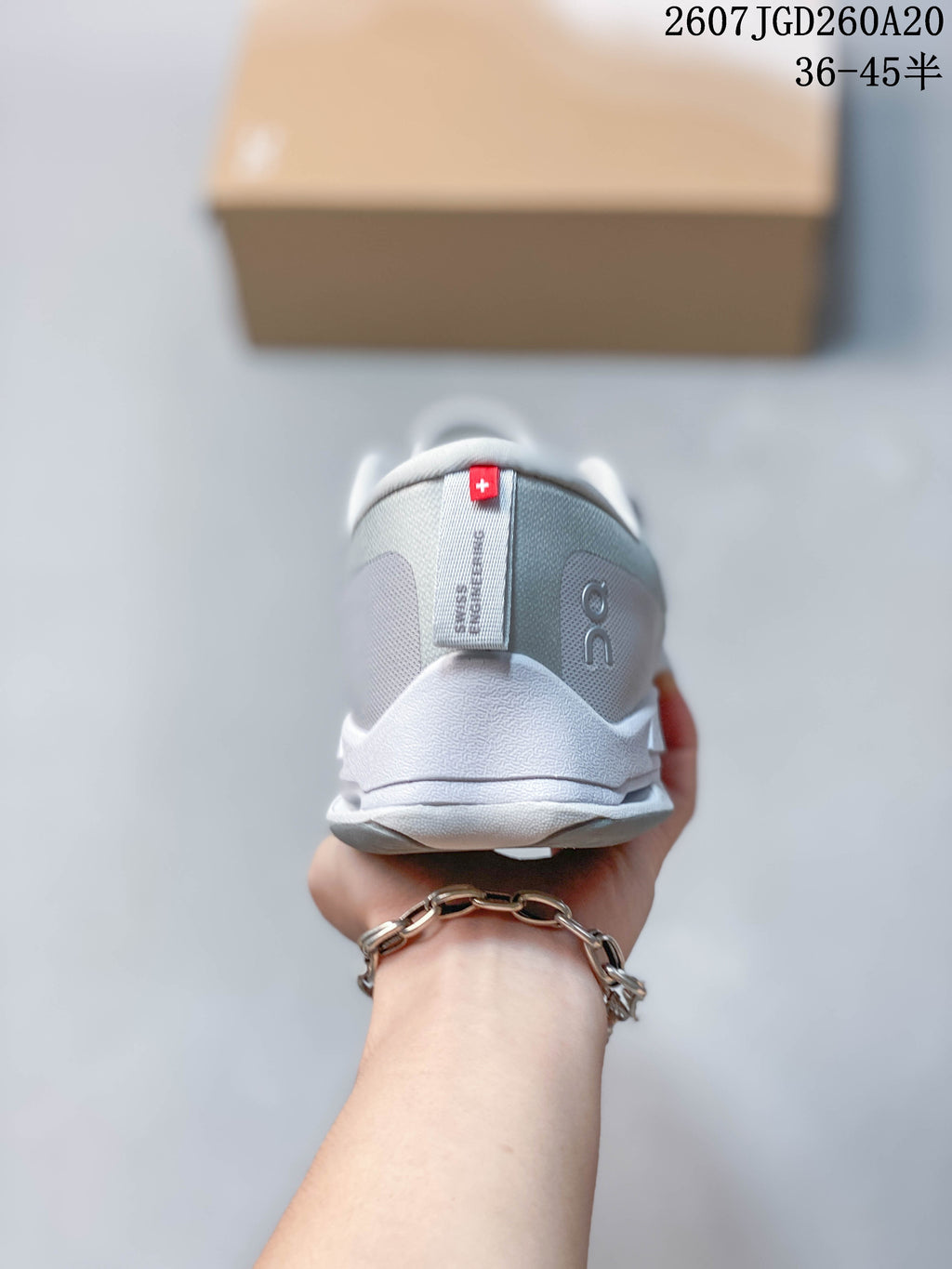 Rear view of the light gray sneaker showing the padded heel collar, On branding, and heel pull detail.