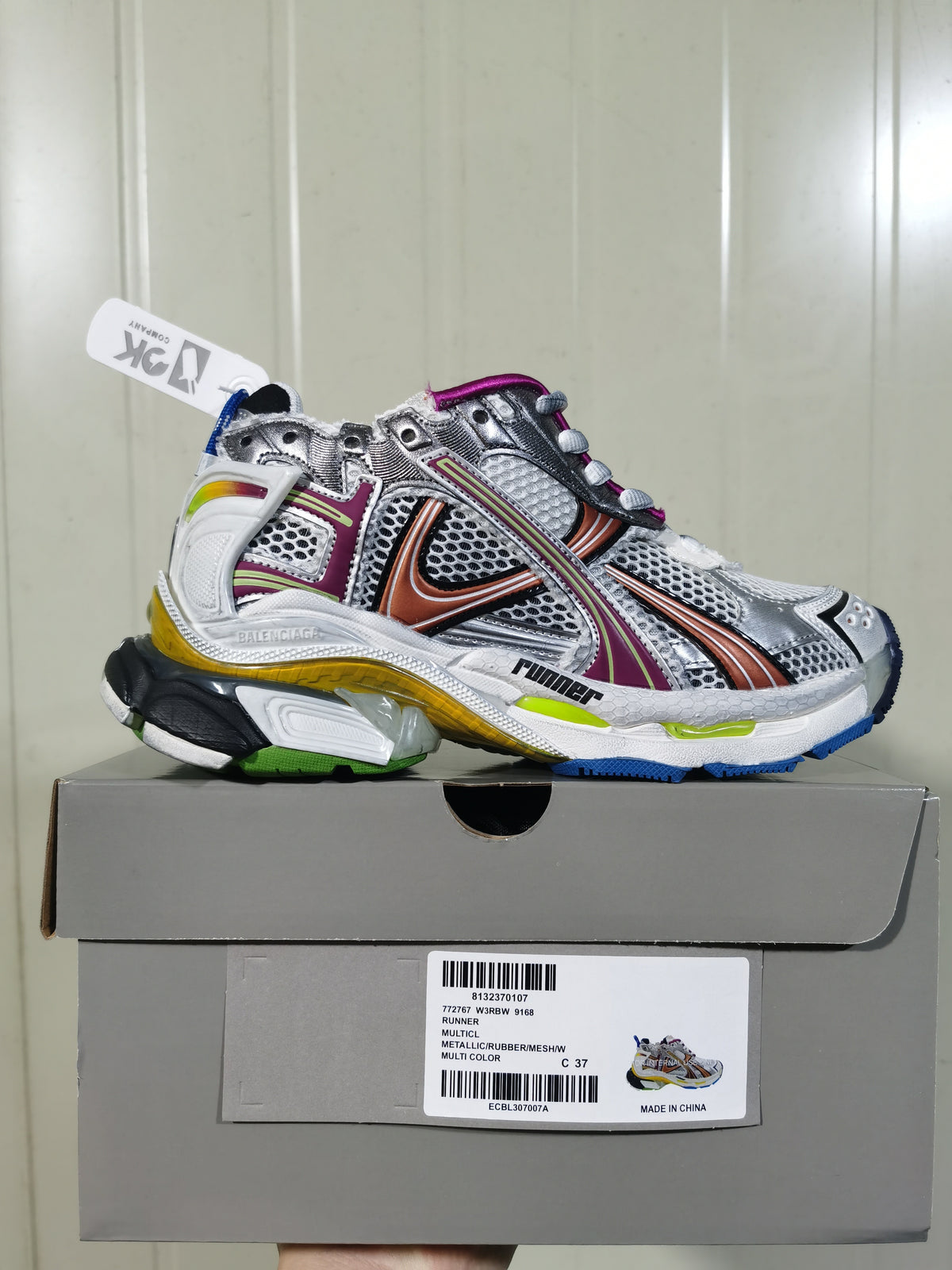Side view of the metallic multicolor Runner sneaker displayed on its shoe box; the box label shows Runner product text and a C 37 size marking.