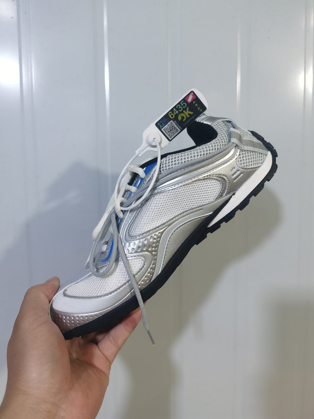 Silver Balenciaga Radar sneaker shown from an angled side view, with layered mesh panels, metallic-look overlays, white laces, and a black outsole.
