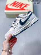 Side profile showing the low-top gray and white sneaker, navy Swoosh, white midsole, and dark navy outsole.
