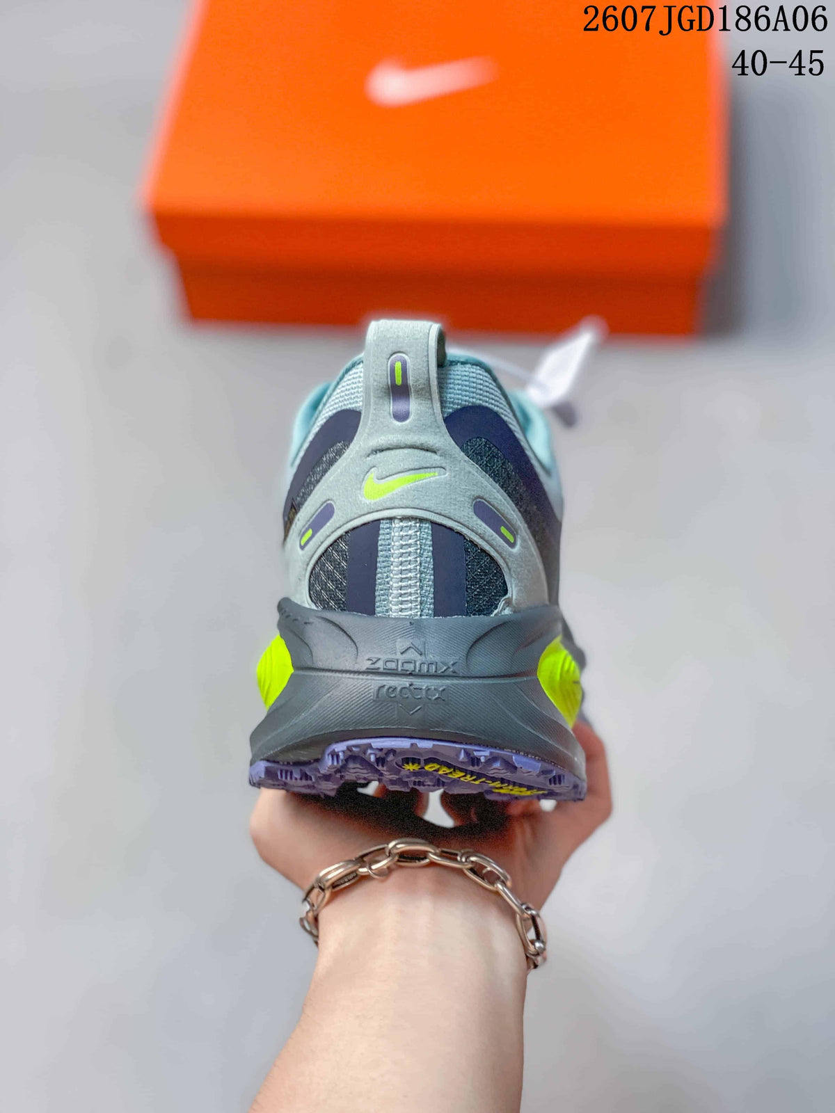 Rear view of the gray sneaker showing the heel pull tab, layered heel structure, neon yellow details, and purple outsole.