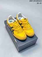 Pair of yellow and black Onitsuka Tiger Serrano sneakers displayed on a shoe box.