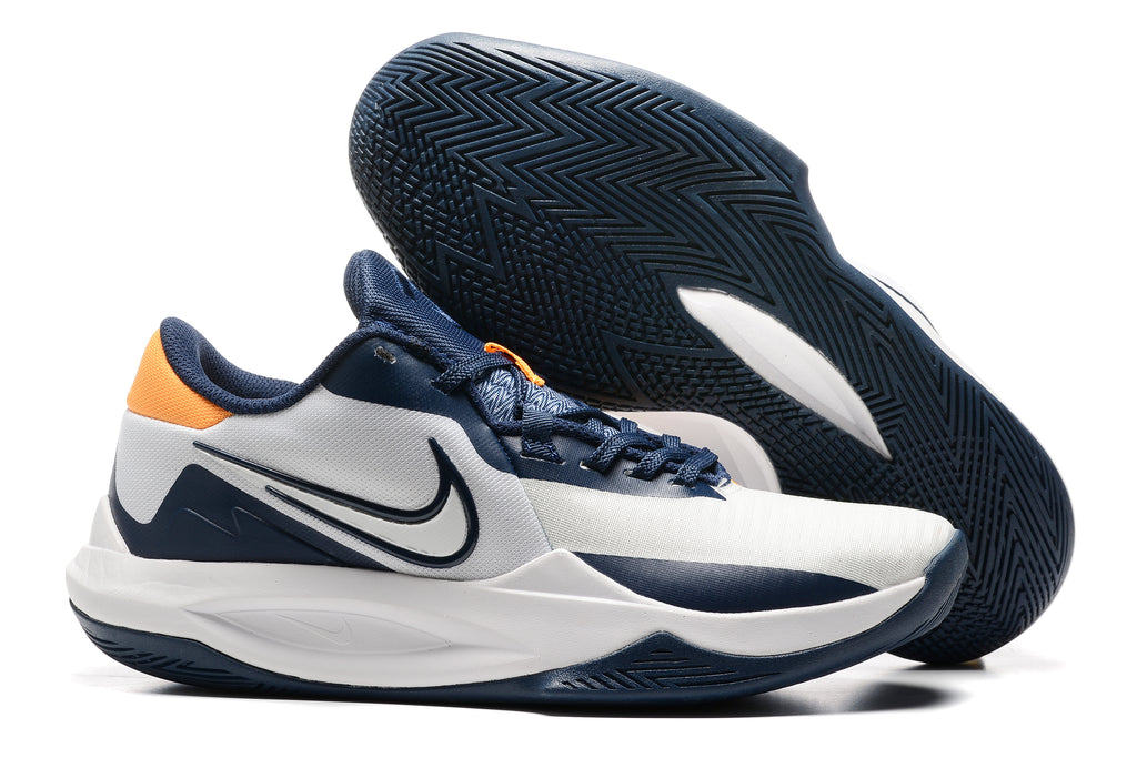 White and navy basketball shoe with orange heel accents.