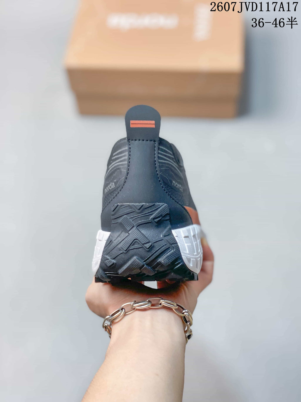 Rear view showing the heel pull tabs, dark upper, orange detail, and segmented white midsole.