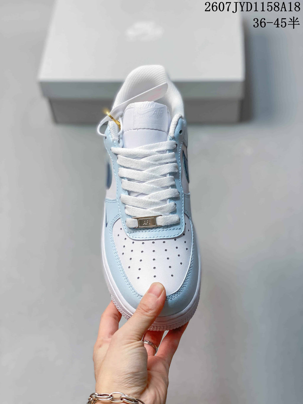 Top view of the sneaker showing white laces, a perforated white toe box, light blue overlays, and a decorative lace plate.