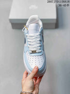 Top view of the sneaker showing white laces, a perforated white toe box, light blue overlays, and a decorative lace plate.