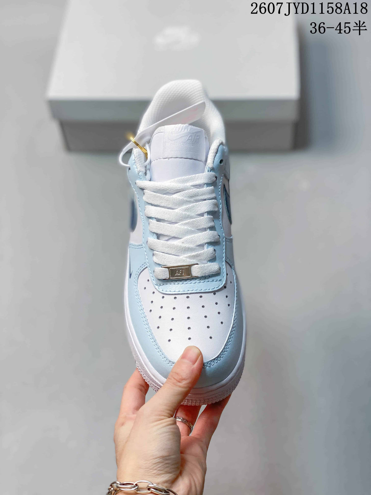 Top view of the sneaker showing white laces, a perforated white toe box, light blue overlays, and a decorative lace plate.