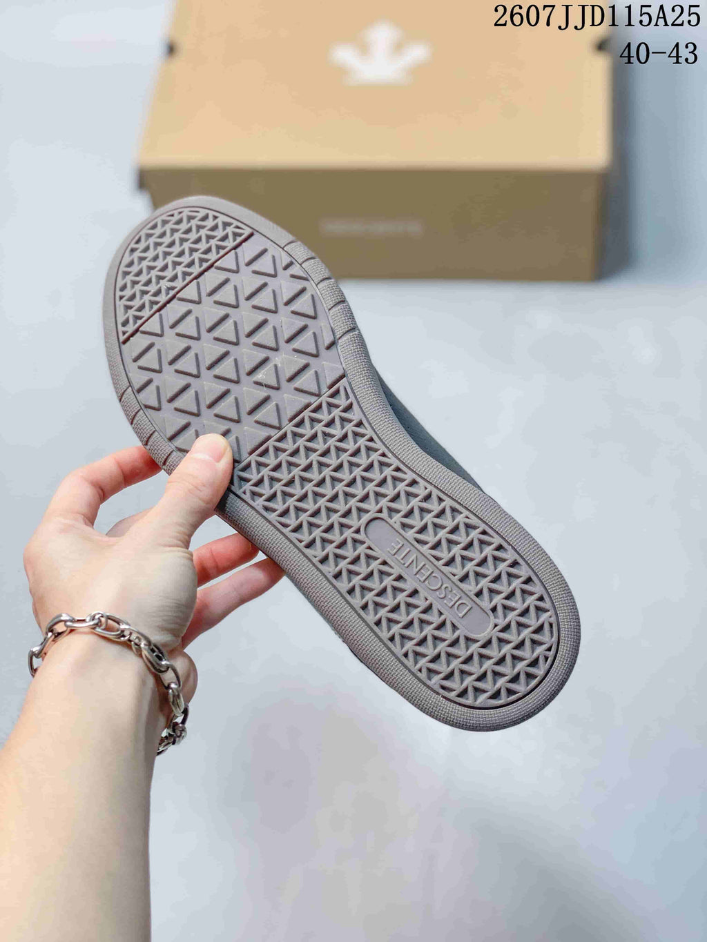 Close view of the sneaker outsole showing a geometric textured tread and Descente branding.