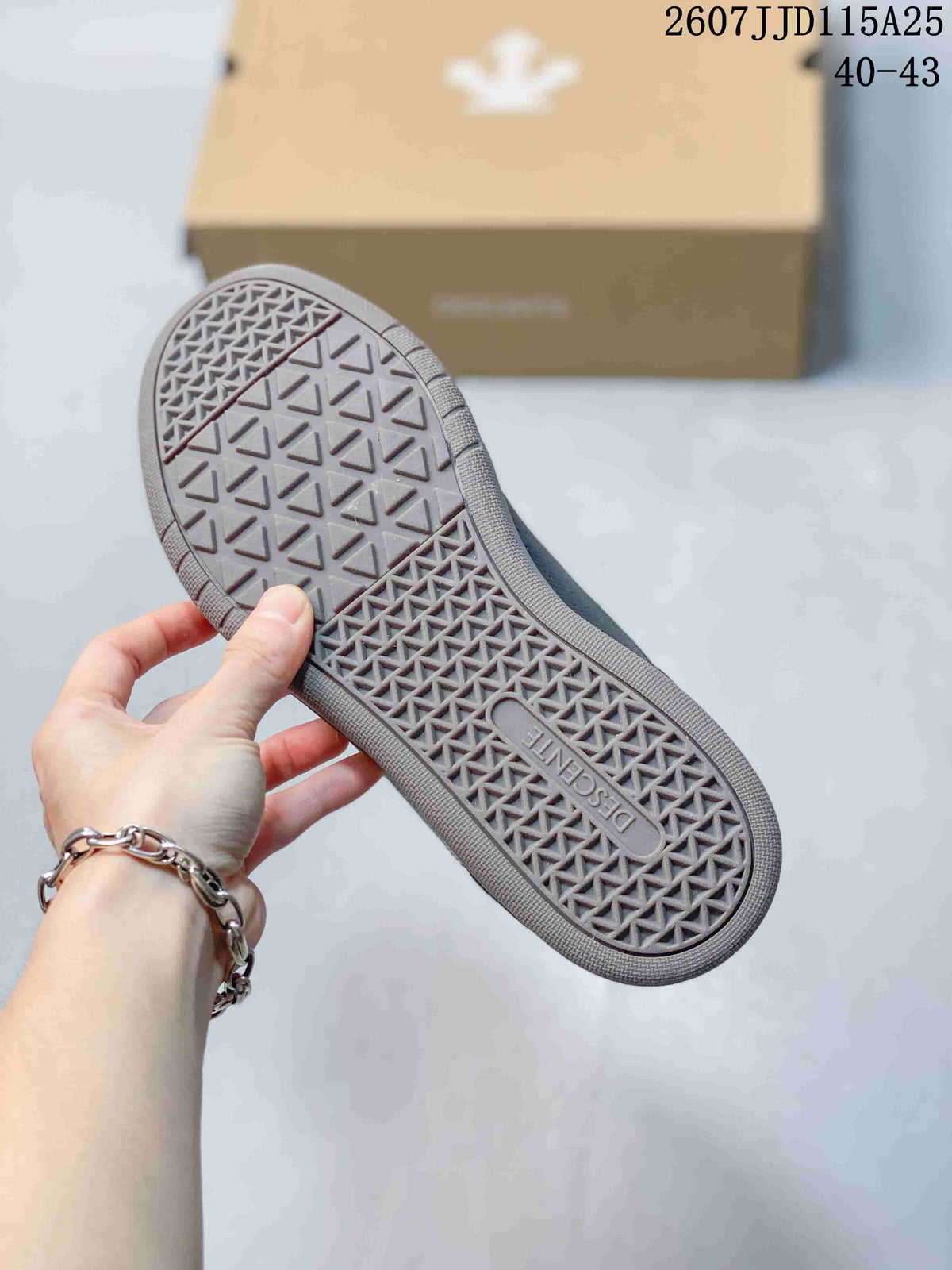 Close view of the sneaker outsole showing a geometric textured tread and Descente branding.