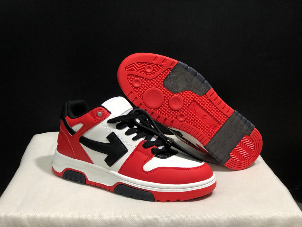 Angled view of the sneakers with one shoe lifted to reveal the red and black patterned outsole.