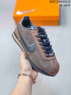 Side view of a dark brown Nike Classic Cortez sneaker with black Swoosh, dark outsole and contrasting tan midsole detail.