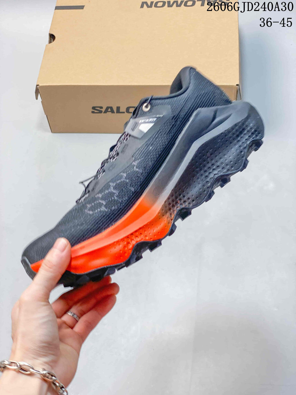 Side view of a charcoal-gray Salomon Ultra Glide 4 with orange midsole accents and a lugged outsole.