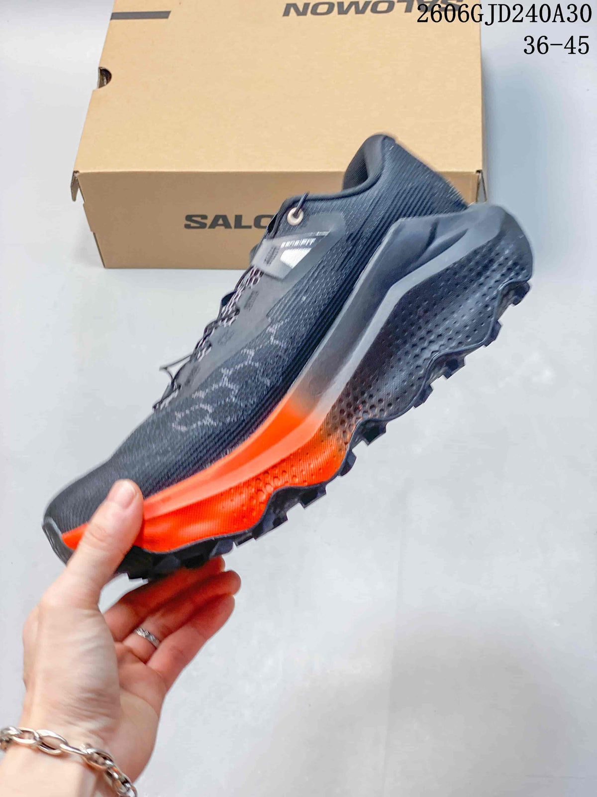 Side view of a charcoal-gray Salomon Ultra Glide 4 with orange midsole accents and a lugged outsole.