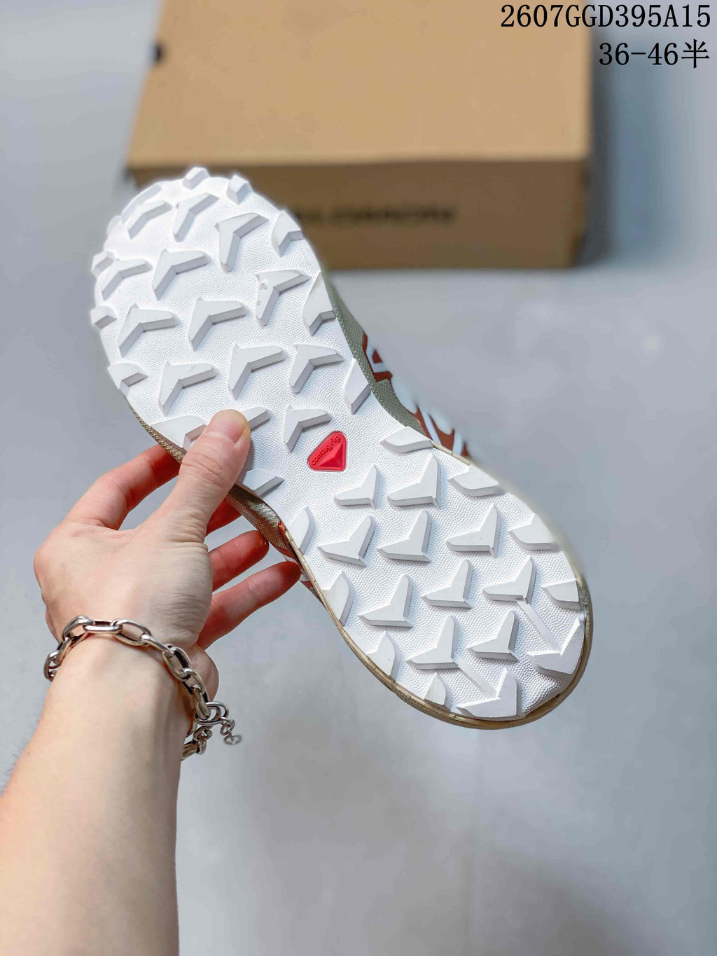 Close-up of the white lugged outsole with directional tread and a red Salomon mark; product code and size range are overlaid.