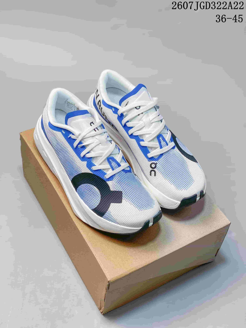Pair of white, blue and black On running shoes displayed on a cardboard box; overlay shows style reference 2607JGD322A22 and size range 36–45.