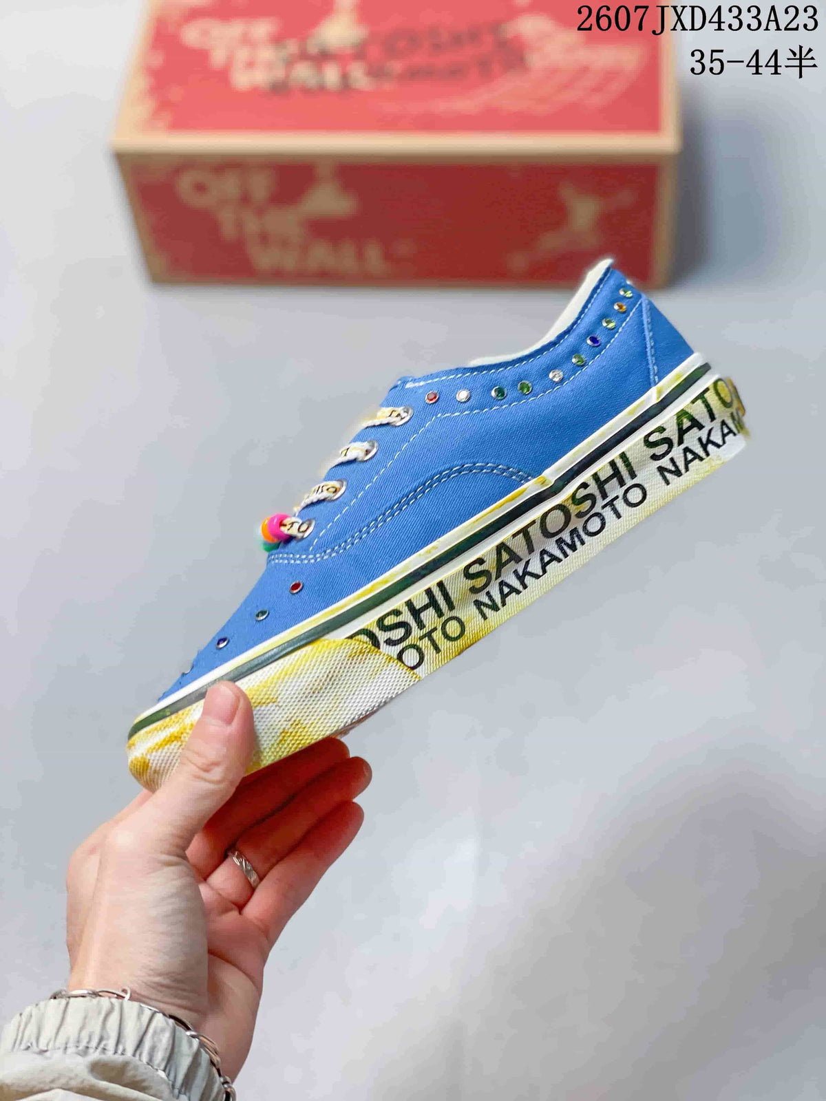 Side profile of the blue canvas sneaker showing contrast stitching, decorative eyelets, printed sidewall graphics, and the rubber outsole.