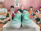 Front view of mint-green basketball sneakers with red tongue details and white soles.