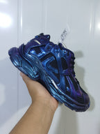 Angled front and side view highlighting the metallic blue-purple colorway, black mesh and sculpted outsole.