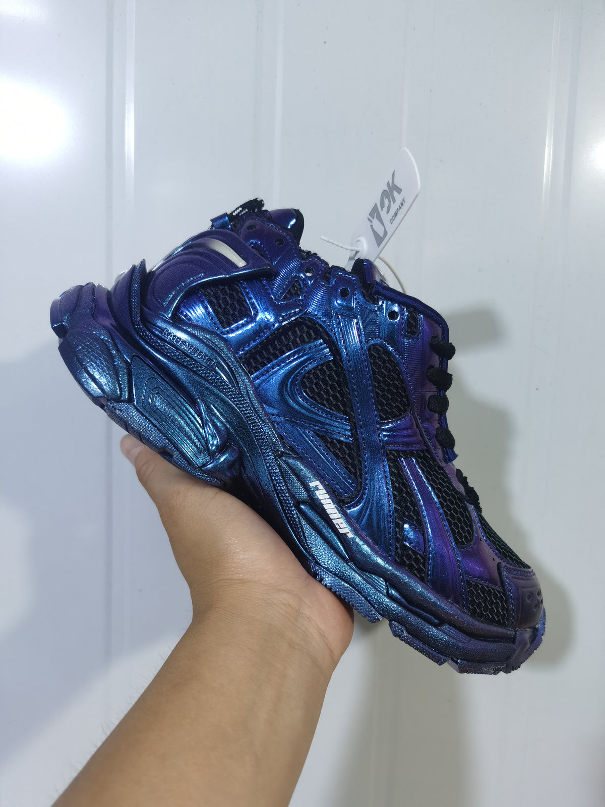 Angled front and side view highlighting the metallic blue-purple colorway, black mesh and sculpted outsole.