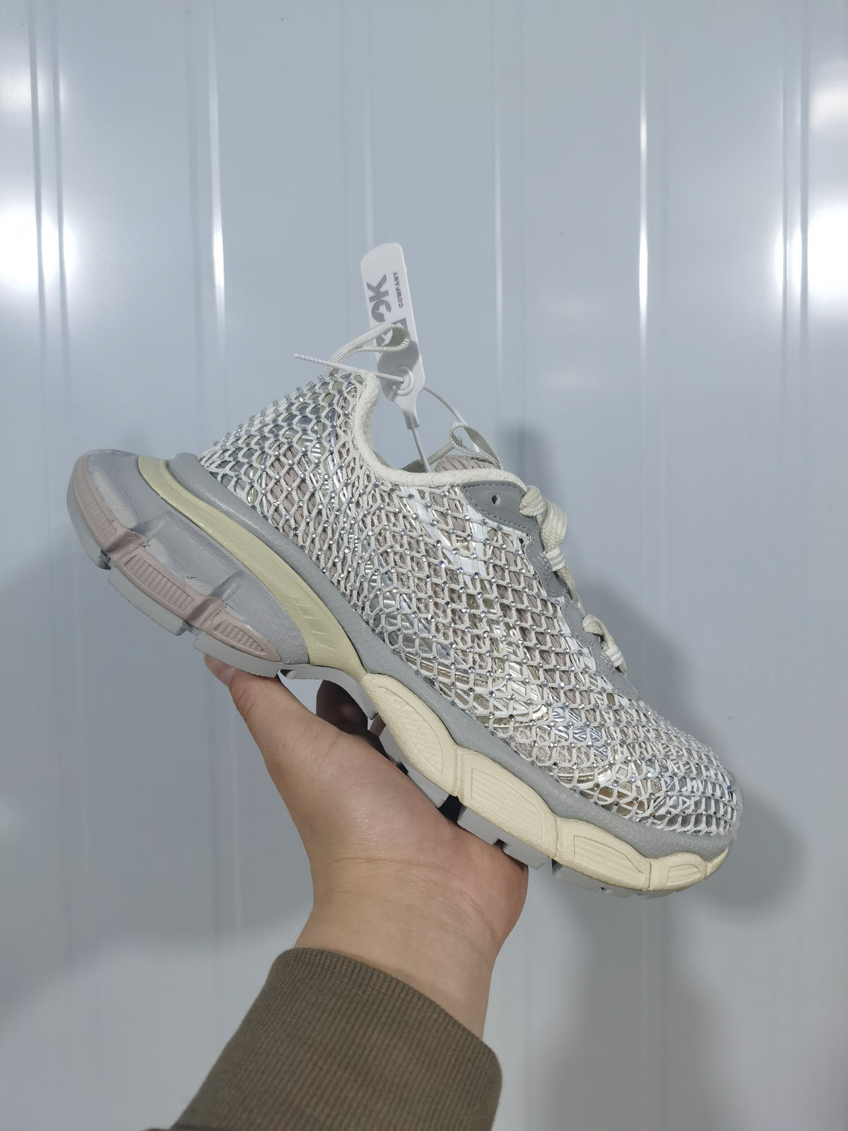 Angled close view showing the open mesh-style upper, reflective detailing, gray overlays, and segmented sole.
