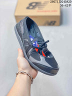 Angled side view showing the black and gray upper, lace-up closure, layered panels, and outsole.