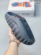 Close side view of a black Nike Mind 001 slide showing the perforated upper, side swoosh, and sculpted outsole.
