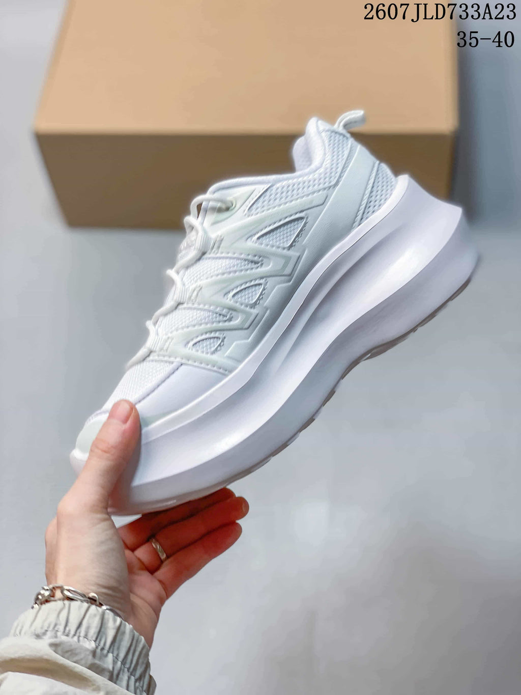Side profile of a white sneaker showing the layered upper panels, mesh sections and raised midsole.
