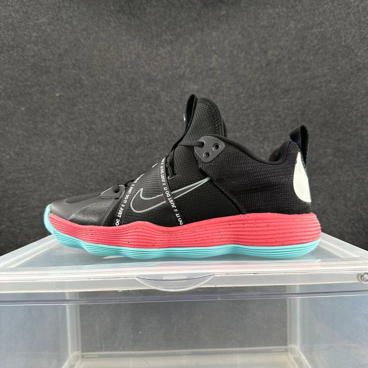 Side view of black Nike basketball shoes with a gray Swoosh, pink midsole, turquoise outsole accents, and a printed cross-lacing strap.