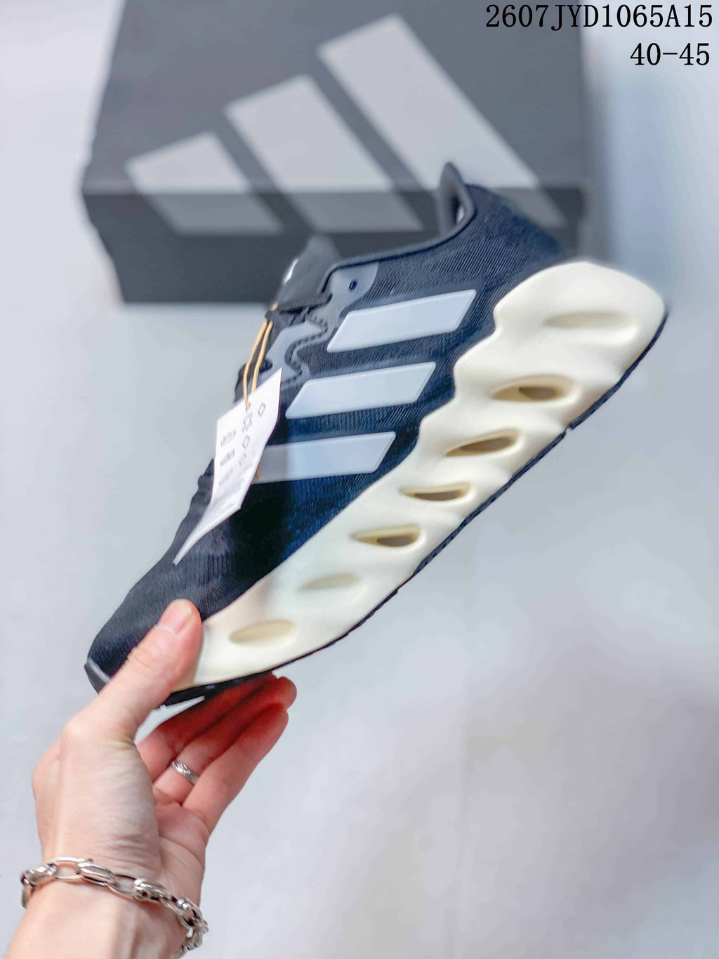 Side profile of the sneaker showing white side details, dark upper and sculpted midsole openings.