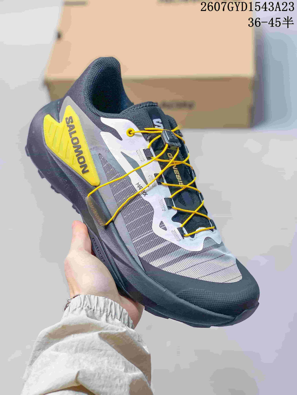 Dark gray Salomon Genesis shoe with yellow quick-lace cord and a yellow heel overlay.