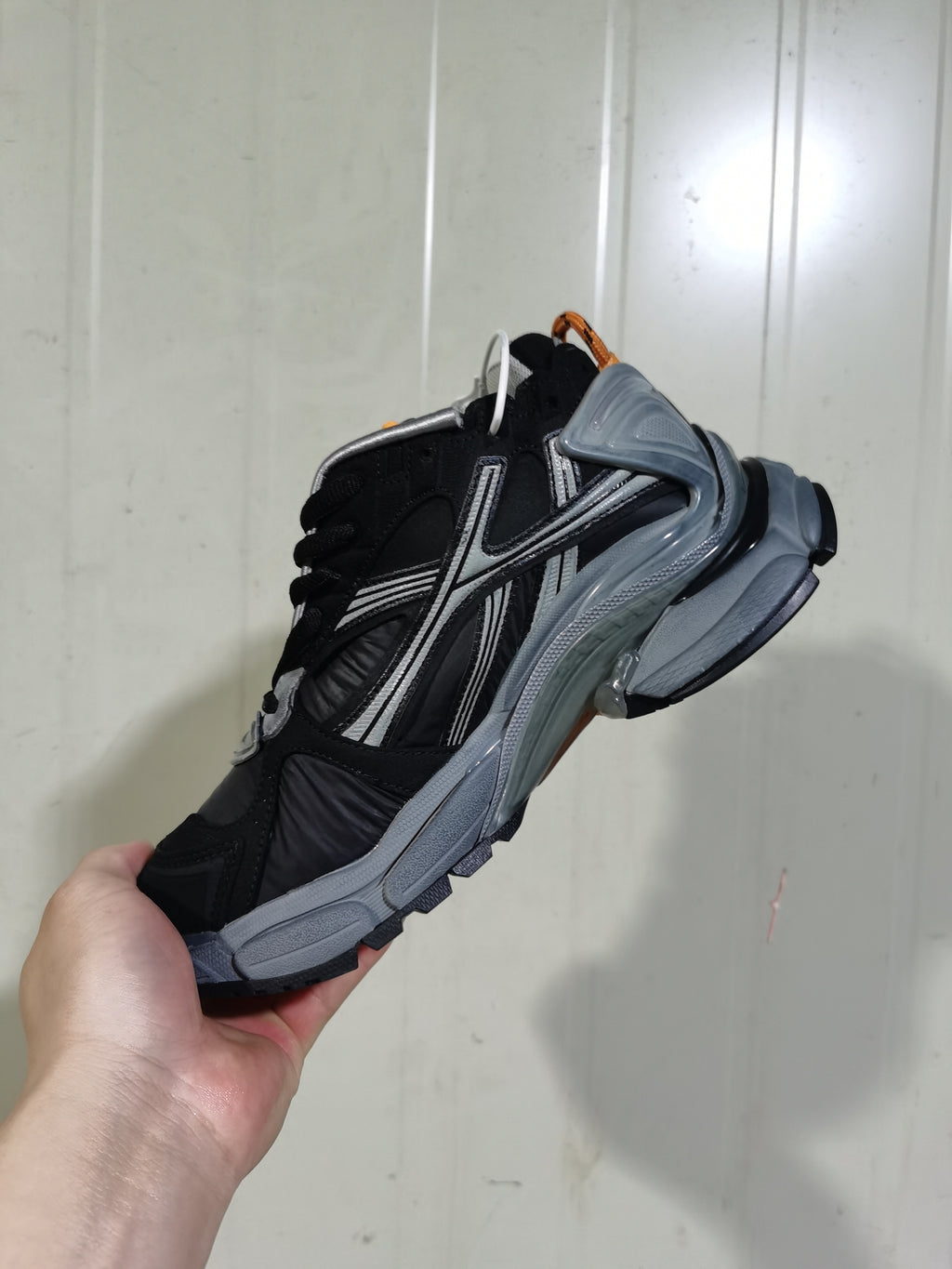 Angled view of the black and grey sneaker showing the layered upper, side detailing, padded collar and chunky sole.