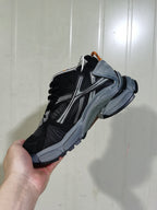Angled view of the black and grey sneaker showing the layered upper, side detailing, padded collar and chunky sole.