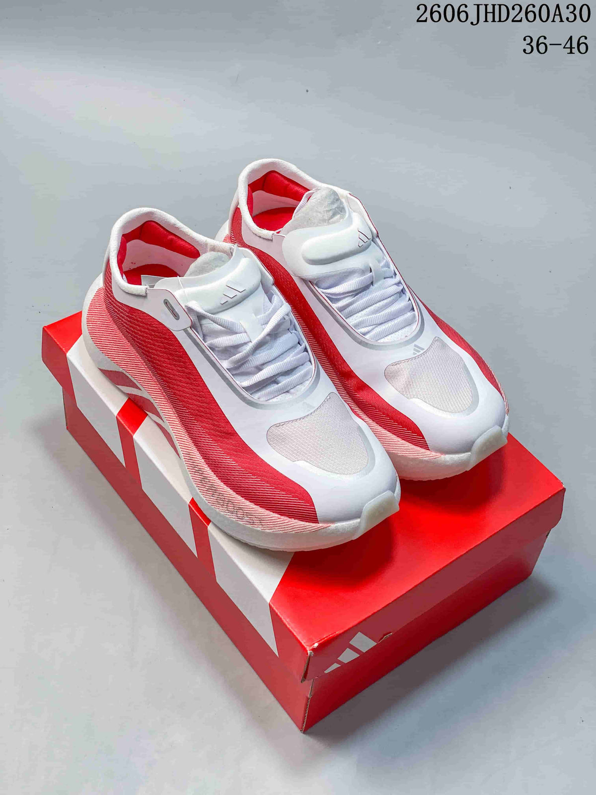 Pair of red and white adidas Hyperboost Edge M running shoes on a red box