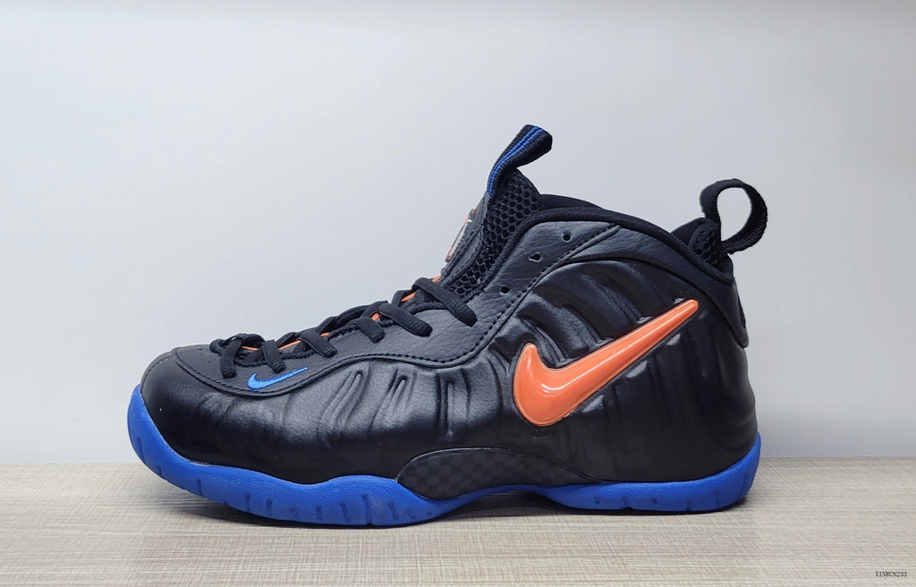 Side view of a black Nike Air Foamposite Pro sneaker with an orange Swoosh and blue outsole.