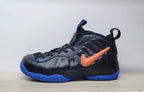 Side view of a black Nike Air Foamposite Pro sneaker with an orange Swoosh and blue outsole.