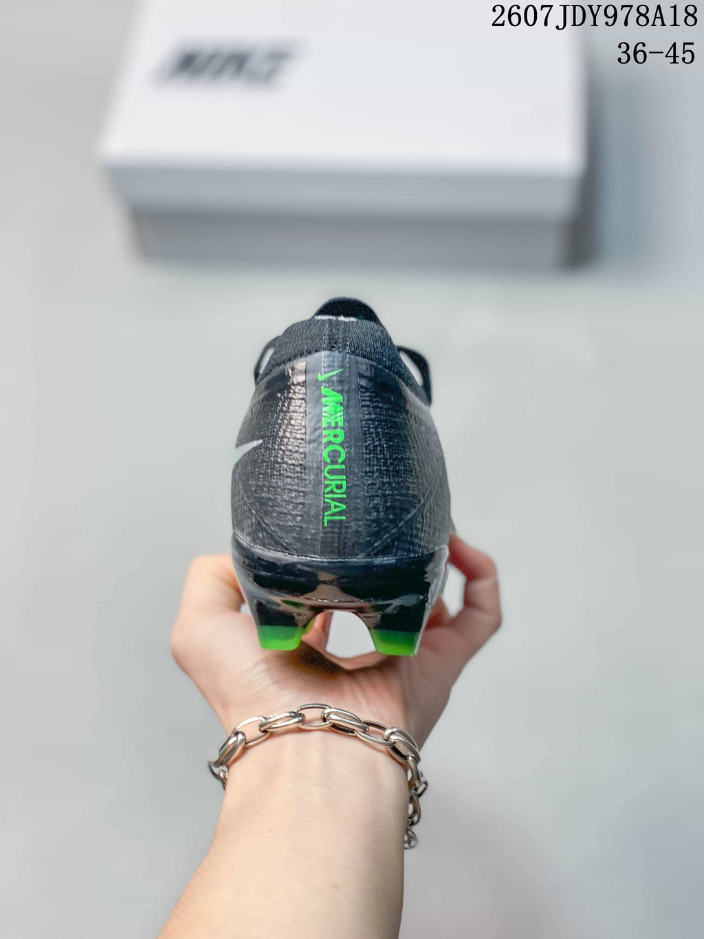 Rear view showing the black heel counter, green Mercurial lettering, and rear studs.