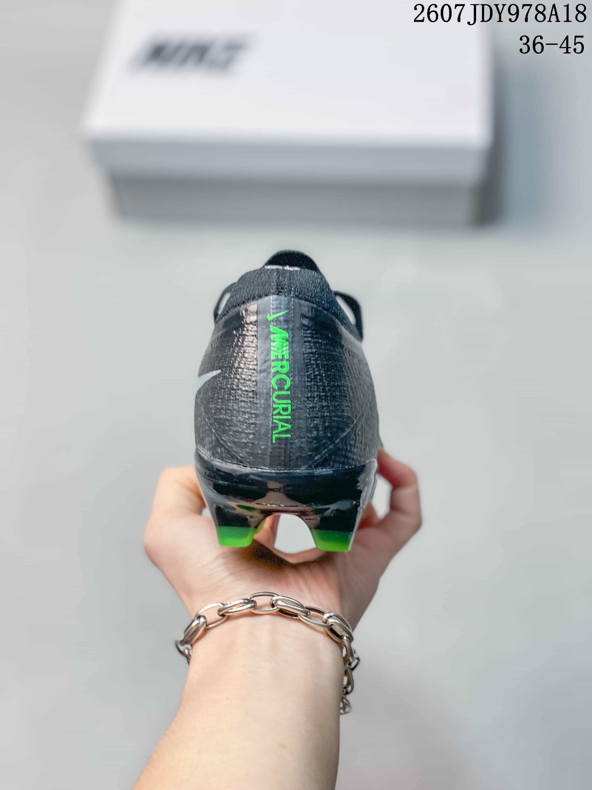 Rear view showing the black heel counter, green Mercurial lettering, and rear studs.