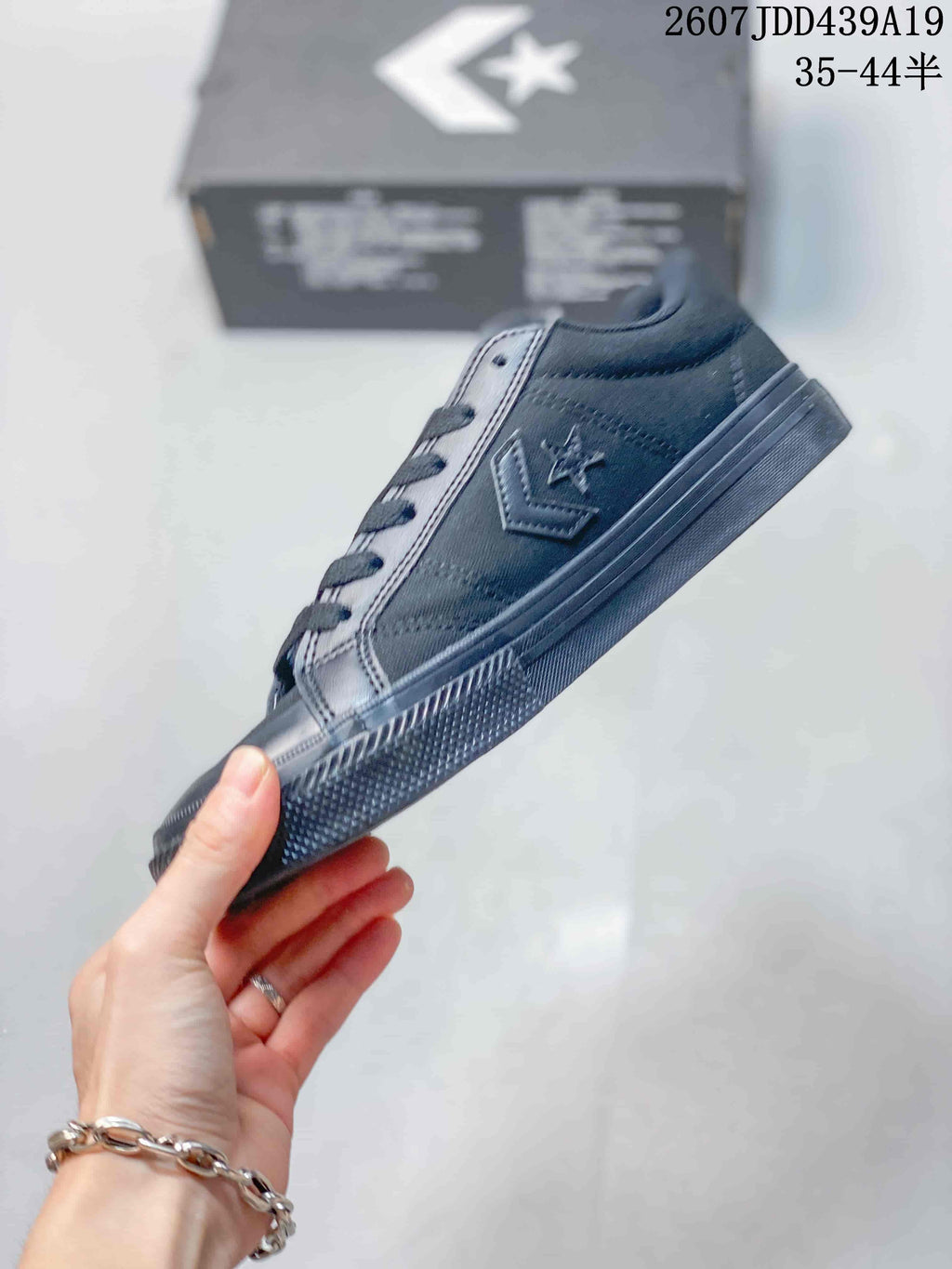 Side view of a black low-top Converse sneaker showing the star-chevron emblem, laces, stitched panels, and rubber sole.