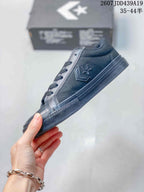 Side view of a black low-top Converse sneaker showing the star-chevron emblem, laces, stitched panels, and rubber sole.