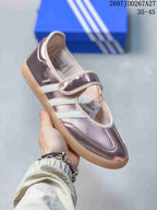Angled side view showing the metallic pink Samba upper, white stripes, adjustable strap and visible Samba marking.