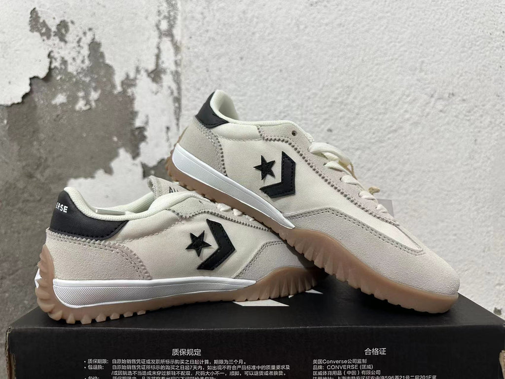 Pair of cream Converse low-top sneakers with black side logos and gum-colored outsoles