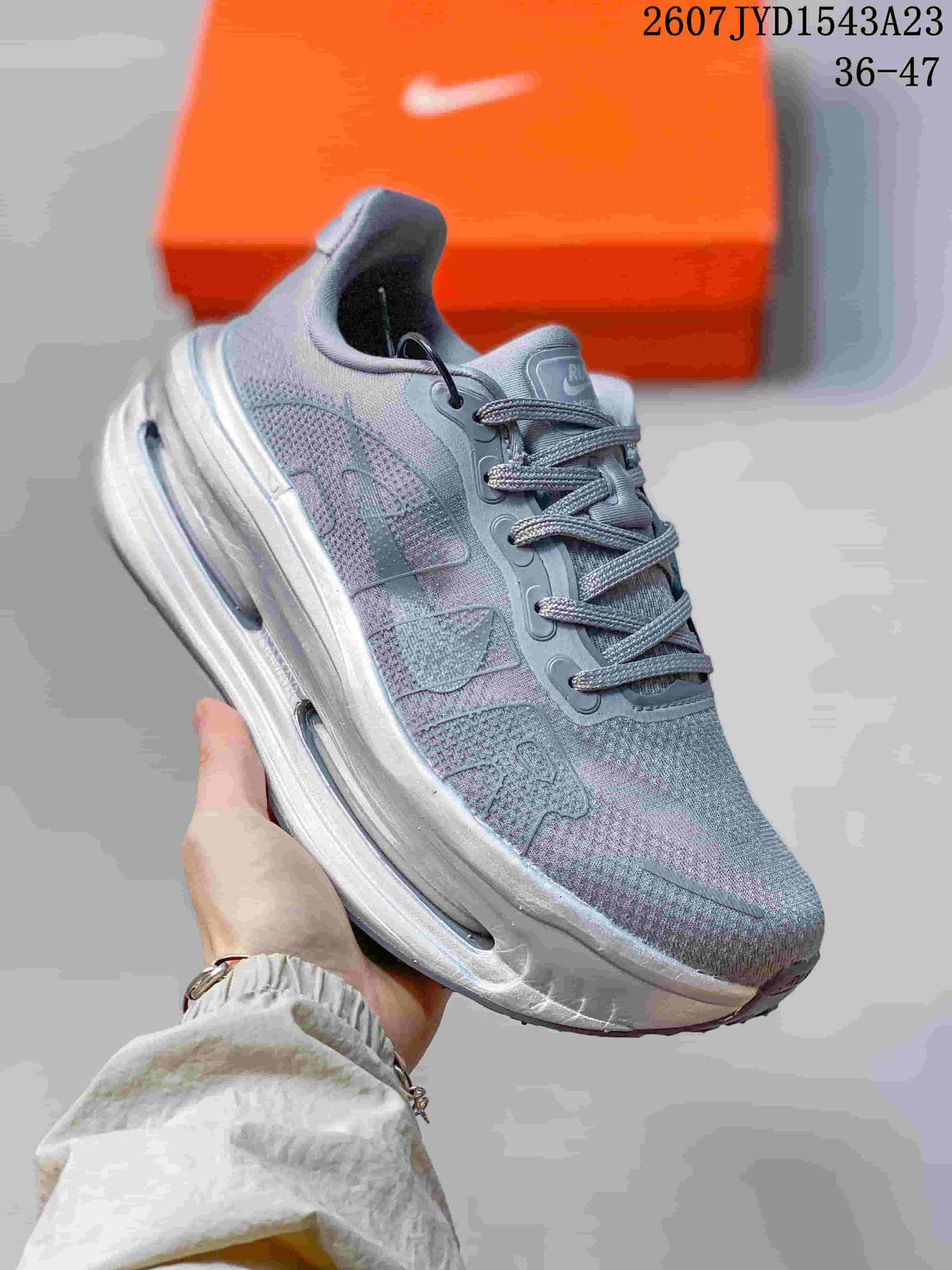 Angled side view of the grey and soft lilac Nike Vomero Premium sneaker showing layered upper panels and a thick midsole.