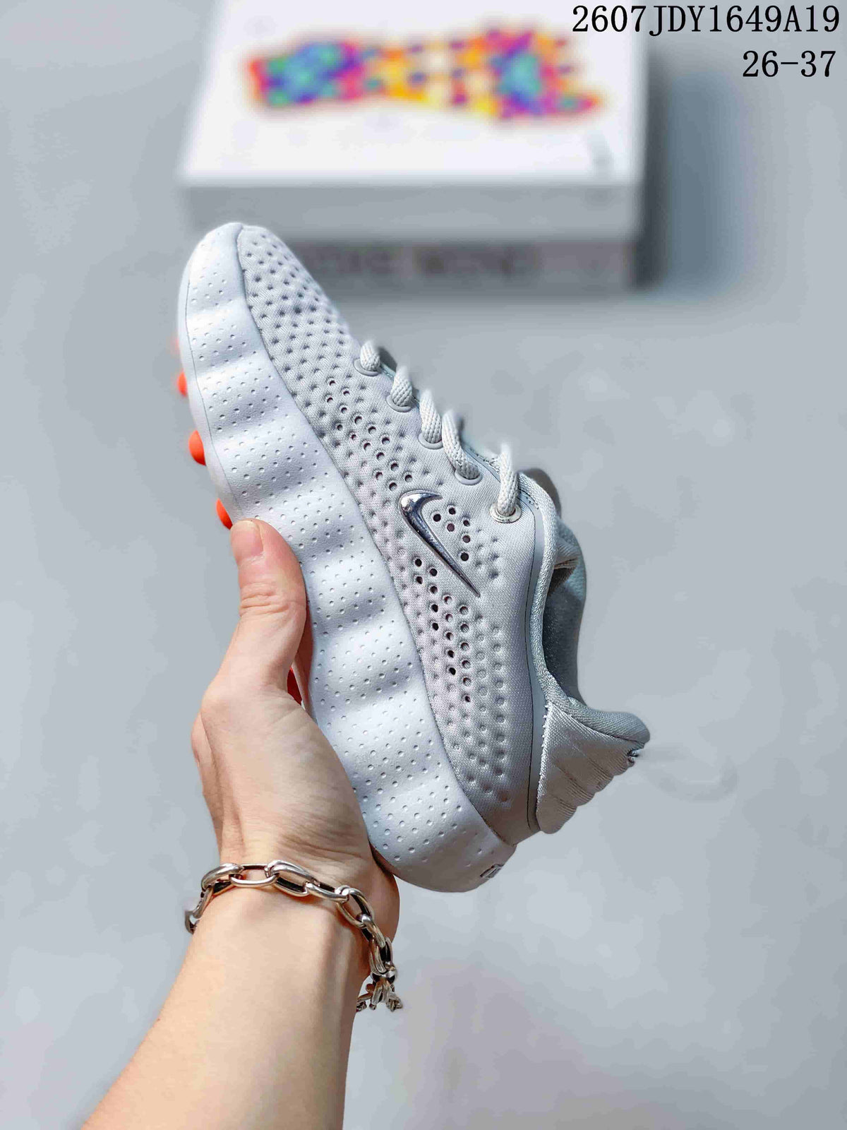 Side profile of a white and grey Nike Mind 002 sneaker showing the perforated upper, side swoosh, and segmented sole.