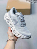 Angled side view showing the gray and white upper, On logo and segmented sole.