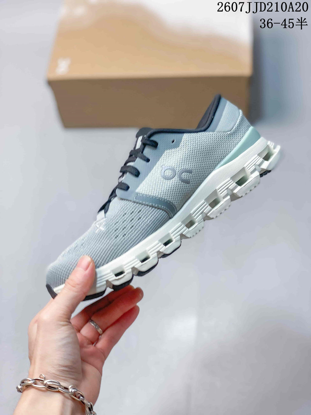 Side view showing the gray upper, On branding, black laces, and structured segmented sole.