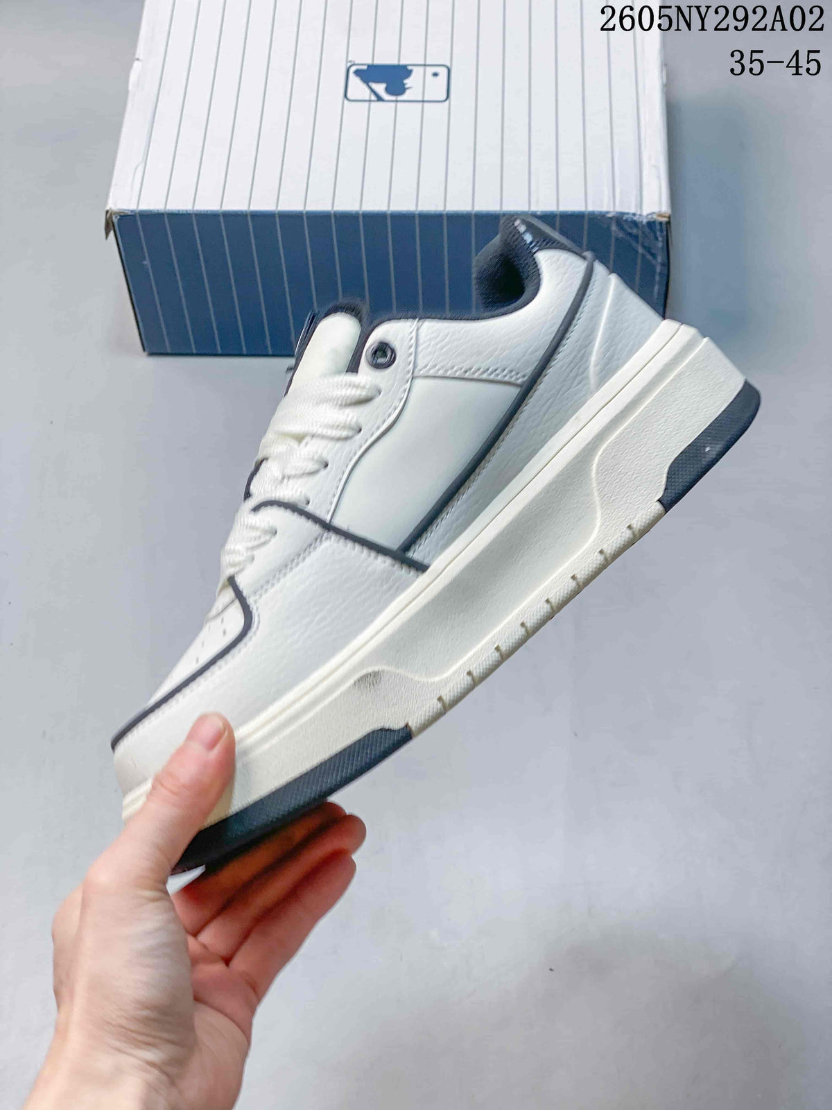 Side view of the white and navy low-top sneaker showing layered panels, dark trim, and a raised sole.
