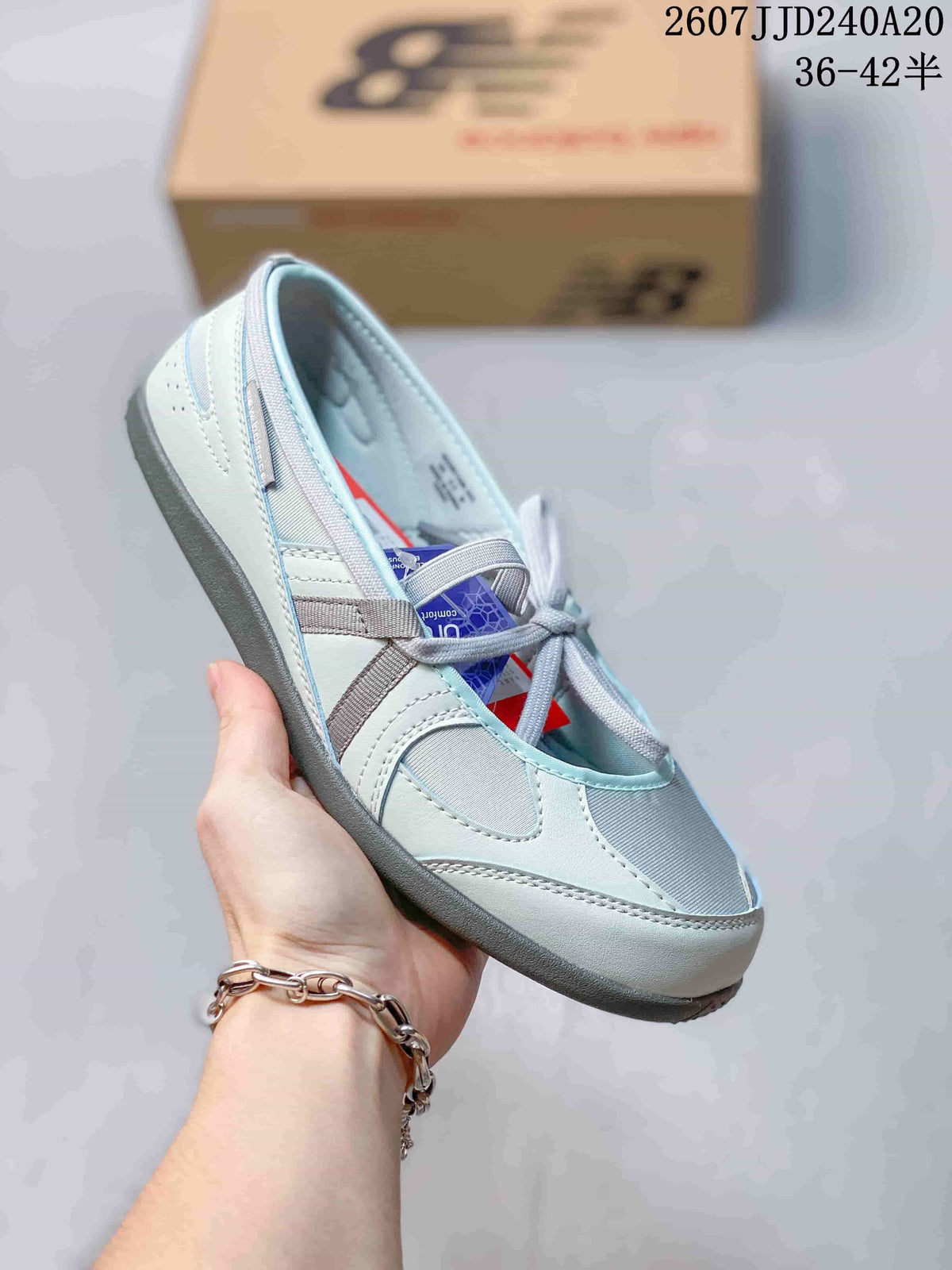 Angled view of the grey New Balance shoe showing the rounded toe, panel stitching, and outsole.